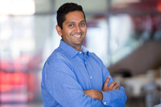 Image of Bharath Chandesekaran, man with dark hair in a blue shirt with arms crossed